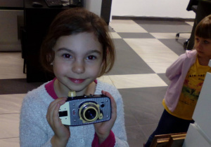 Dziewczynka pokazuje stary aparat fotograficzny.